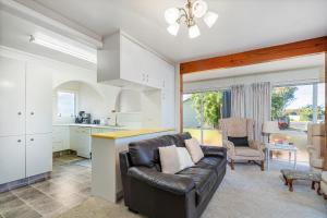 a living room with a couch and a kitchen at Williamson Getaway - Top Whangamata Location in Whangamata