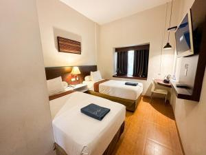a hotel room with two beds and a desk at Hotel De Green Lampung in Lampung