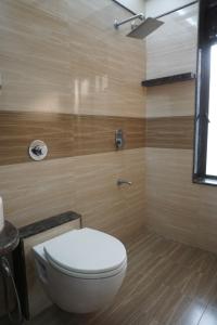a bathroom with a white toilet and wooden walls at S R Rooms in Pune +18 photos