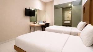 a hotel room with two beds and a television at OS Hotel Airport Batam in Batam Center