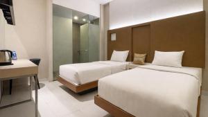 a hotel room with two beds and a desk at OS Hotel Airport Batam in Batam Center +34 photos