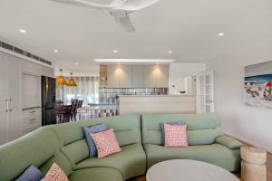 a living room with a green couch and a kitchen at Free night! Pay for 2 stay for 3 in Mollymook