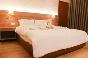 a large white bed in a hotel room at Hotel Lumbini Garden New Crystal in Rummindei +8 photos