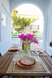 a table with a vase of flowers and plates and glasses at Aroura Homes Spetses 3BR 2BA in Spetses