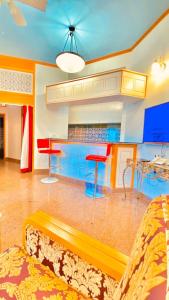 a living room with a kitchen with blue cabinets and red stools at Qurum Heights Hotel in Muscat