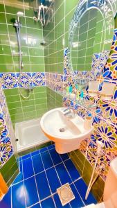 a bathroom with green and blue tiled walls and a sink at Qurum Heights Hotel in Muscat