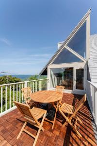 a wooden table and chairs on the deck of a house at 波の音テラス富津ー海眺望グッドデザイン受賞別荘を最大7名1棟貸切 in Futtsu