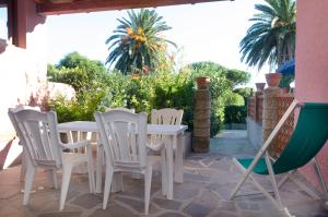 a white table and chairs on a patio with palm trees at Villa Maria Carla in Capoliveri