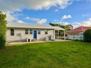 a white house with a blue door and a yard at SUMMER DAYSIES - Pet Friendly WiFi in Robe
