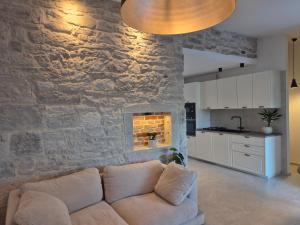 a living room with a couch in front of a stone wall at Mareya Premium Stay in Poreč