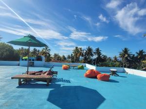 a pool with a bench and an umbrella on top at JIB Hostel RestoBar in Weligama