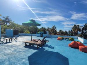 a pool with chaise lounges and an umbrella at JIB Hostel RestoBar in Weligama