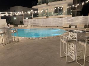 a swimming pool with chairs and a table in front of a building at Terra d'Acqua Resort & SPA in Torre Mozza