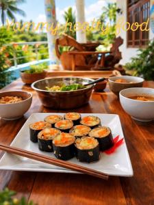 a plate of sushi on a table with bowls of food at JIB Hostel RestoBar in Weligama