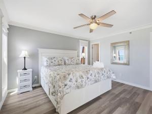 a white bedroom with a bed and a ceiling fan at Kingfisher Oceanfront Condo w Pool & Elevator in North Topsail Beach