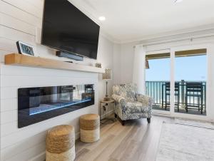 a living room with a fireplace and a tv at Kingfisher Oceanfront Condo w Pool & Elevator in North Topsail Beach