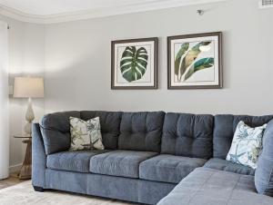a blue couch in a living room with two pictures on the wall at Kingfisher Oceanfront Condo w Pool & Elevator in North Topsail Beach