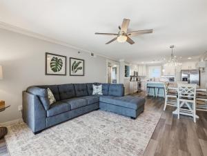 a living room with a blue couch and a ceiling fan at Kingfisher Oceanfront Condo w Pool & Elevator in North Topsail Beach +47 photos