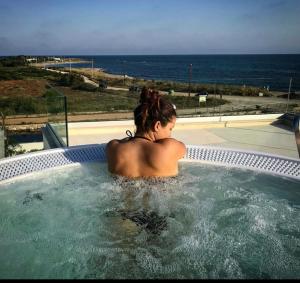 a woman sitting in a hot tub looking at the ocean at Terra d'Acqua Resort & SPA in Torre Mozza