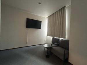 a living room with a couch and a television at TOMAレジデンスホテル TOMA Residence Hotel in Kure