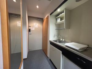 a small kitchen with a sink and a door at TOMAレジデンスホテル TOMA Residence Hotel in Kure