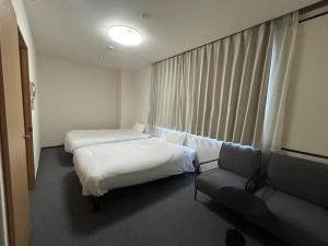 a hotel room with two beds and a couch at TOMAレジデンスホテル TOMA Residence Hotel in Kure