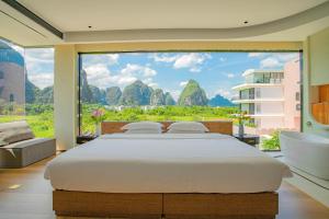 a large bed in a room with a large window at 桂林阳朔良宿 LS Hotel Liangsu Yangshuo in Yangshuo +91 photos