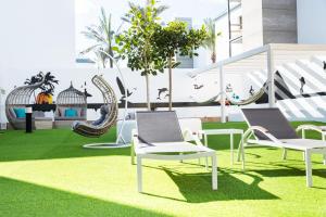 un patio con sillas y columpios en el césped en Corralejo Surfing Colors Hotel&Apartments, en Corralejo