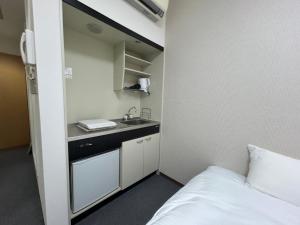 a small bathroom with a sink and a bed at TOMAレジデンスホテル TOMA Residence Hotel in Kure