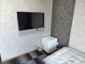 a bedroom with a bed and a flat screen tv on the wall at 五島宿Seina in Goto