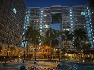 a pool with palm trees and buildings at night at Lamierda Condotel 2 in Iba