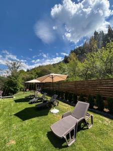a group of chairs and an umbrella on the grass at Villa Camino in Sapareva Banya