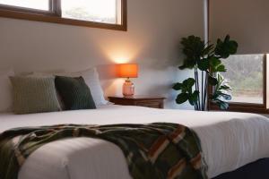 a bedroom with a bed with a lamp and a plant at Camelot in Kingscote