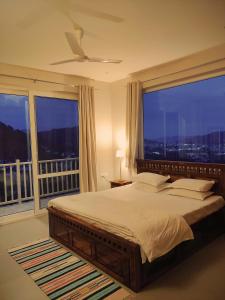 a bedroom with a large bed with a large window at Serai Habitat in Solan