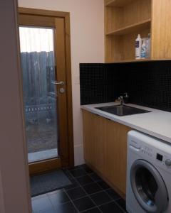 a kitchen with a washing machine and a sink at Camelot in Kingscote