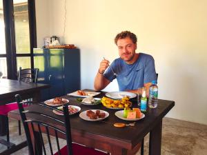 a man sitting at a table with food on it at The LeoEye Wilpattu in Pahala Maragahawewa