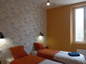 a bedroom with two beds and a wall with flowers at Gite La maison du gardien in Marcillac-Vallon