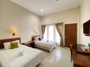 a hotel room with two beds and a television at Urbanview Hotel Ratna Syariah in Sukobumi