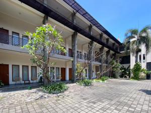 a courtyard of a building with trees and palm trees at Urbanview Hotel Ratna Syariah in Sukobumi