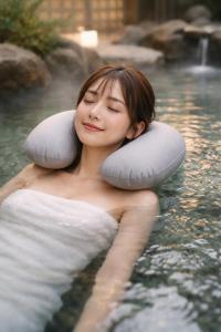 a woman sitting in the water with pillows around her shoulders at Good Stay Mizuho in Usa