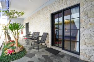 a patio with a table and chairs and a stone wall at The Lavana Infinity Jogja Villa in Salakan