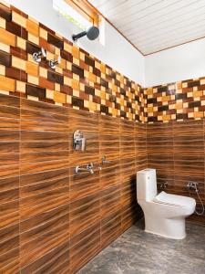 a bathroom with a toilet and wooden walls at Athiti Devo Bhava in Chakrāta +2 photos