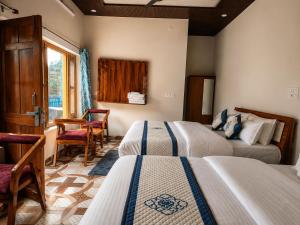 a bedroom with two beds and a table and a desk at Athiti Devo Bhava in Chakrāta