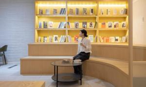 a woman sitting on a bench in a library at Cheongju Hotel Dictionary in Cheongju