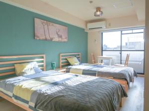 two beds in a room with blue walls at 9Stay川崎 in Kawasaki