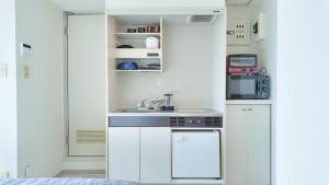 a small kitchen with white cabinets and a sink at 9Stay川崎 in Kawasaki