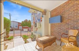 a patio with a bench and a tv on a brick wall at Bank-sia accommodation in Mount Barker