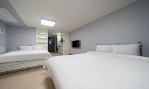 a bedroom with two beds and a television in it at Myeongga Ubleth Hotel in Yeosu