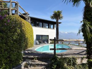 a house with a swimming pool and a palm tree at La Finestra sul lago in Brissago