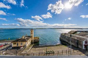 a pier with a lighthouse on a body of water at Unit 5 Stunning Oceanview Apartment in Cobh +3 photos